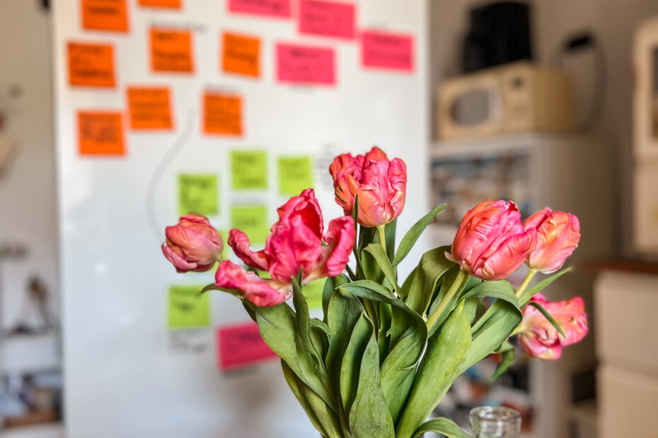 Foto zeigt einen Tulpenblumenstrauß in einer Vase und dahinter eine weiße Magnetwand mit pinken post-it's.